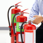 Office,Man,Checking,The,Handle,Of,The,Red,Fire,Extinguishers