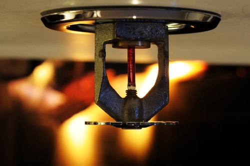 Close,Up,Image,Of,Fire,Sprinkler,With,Fire,In,Background.